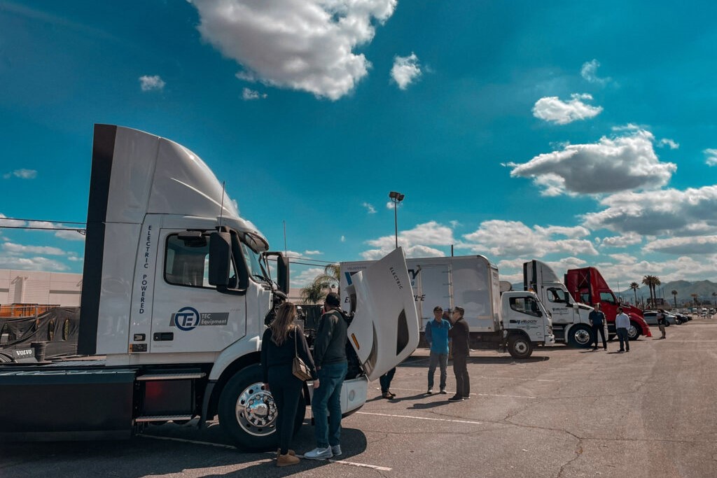 Several heavy duty tractors are lined up in a parking lot under a bright blue sky.